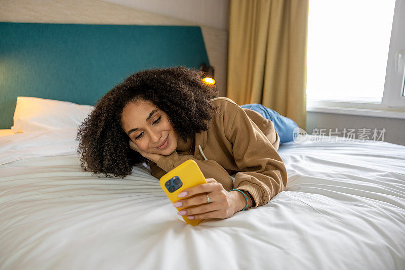 Dark-haired young woman with a phone in hands on the bed